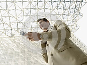 Businessman Reading SMS On Mobile Phone Under Ceiling