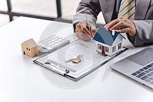 Businessman realtor with house model, sitting at desk, real estate agent manager working on documents, mortgage and property