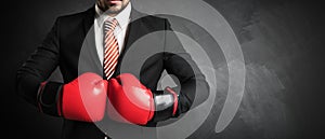 Businessman with red boxing gloves in front of chalkboard