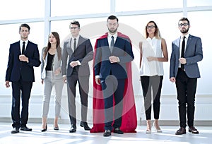 Businessman in a red superhero cloak and his business team