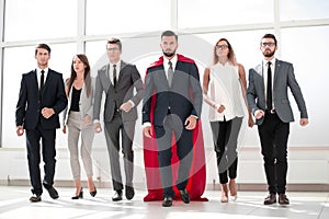 Businessman in a red superhero cloak and his business team