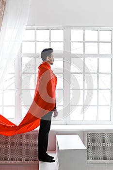 Businessman in red superhero cloak. Young man in suit and superman cape on stairs
