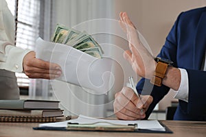 Businessman rejecting bribe at table in office, closeup