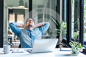 Businessman relaxing with closed eyes while working on laptop at home office