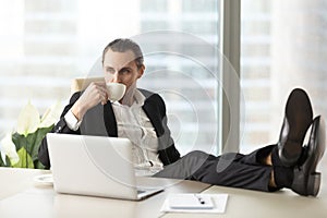 Businessman relaxing and drinking coffee at workplace in office.