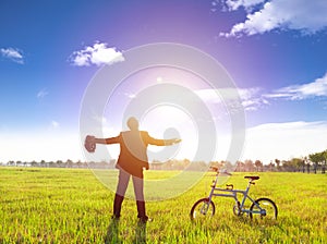 Businessman relaxing in green land and sun with bicycle