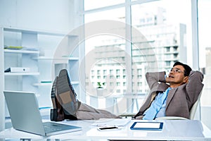 Businessman relaxing with his feet on his desk