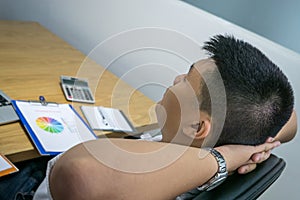 Businessman relaxing at office with hands behind head