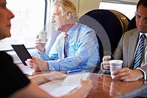 Businessman Relaxing On Train With Cup Of Coffee