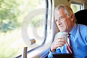 Businessman Relaxing On Train With Cup Of Coffee