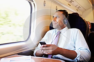 Businessman Relaxing On Train Listening To Music