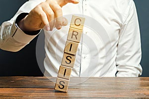 Businessman removes wooden blocks with the word Crisis. The exit from the crisis and financial stability. Focus on resolving the