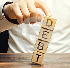 Businessman removes wooden blocks with the word Debt. Debt relief or cancellation is the partial or total forgiveness of debts, or