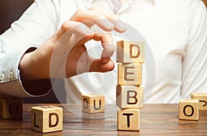 Businessman removes wooden blocks with the word Debt. Reduction or restructuring of debt. Bankruptcy announcement. Refusal to pay photo