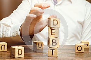 Businessman removes wooden blocks with the word Debt. Reduction or restructuring of debt. Bankruptcy announcement. Refusal to pay