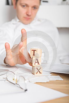 Businessman removes wooden blocks with the word Tax. Reduction or restructuring of debt. Bankruptcy announcement. Refusal to pay