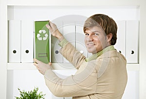 Businessman removing green folder from shelf