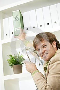 Businessman removing green folder from shelf