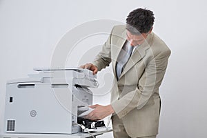 Businessman Removing Paper Stuck In Printer