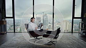 Businessman resting in chair with newspaper. Manager reading newspaper in office