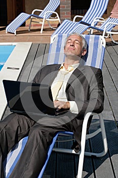 Businessman resting on deck chair