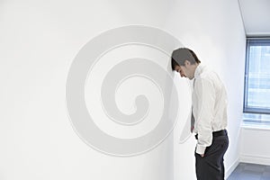 Businessman Resting Head Against Wall