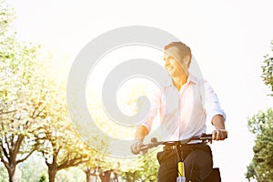 Businessman riding bicycle during sunny summer day in park