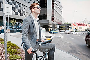 Businessman riding bicycle to work on urban street in morning.