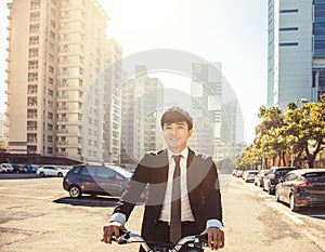 Businessman riding bicycle to work on urban street at morning