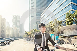 Businessman riding bicycle to work on urban street at morning