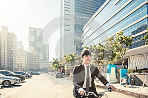 Businessman riding bicycle to work on urban street at morning