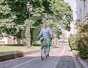 Businessman riding bicycle to work on urban street in morning.