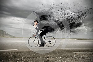 Businessman riding a bike with an umbrella