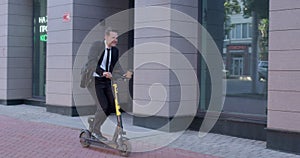businessman riding electric scooter while commuting to work in city, having fun