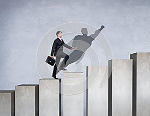 Businessman rise up on the career ladder with superhero shadow on the wall.