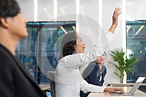 Businessman rises hand up for the question in the diverse employees business people team group. The colleagues discussing and