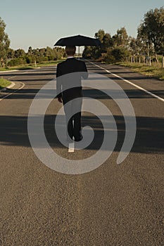 Businessman on the road with umbrella