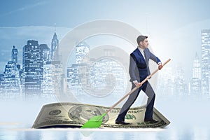 The businessman rowing on dollar boat in business financial concept