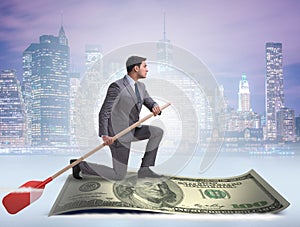 Businessman rowing on dollar boat in business financial concept