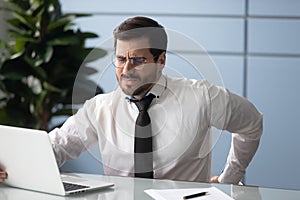Businessman rubbing aching back feels unhealthy, sedentary work concept photo