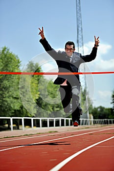 Businessman running on athletic track celebrating victory in work success concept