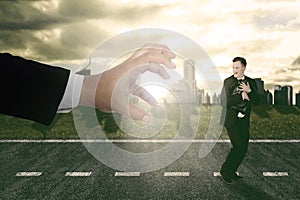 Businessman running scare being chased by a big hand