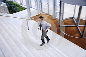 Businessman Running Upstairs In Office Lobby