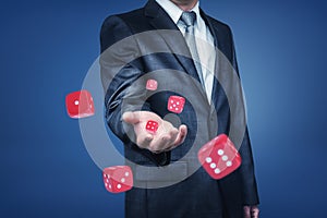 A businessman`s arm throwing many red casino dice to the front in a close view.