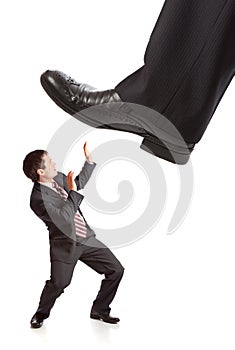 Businessman's foot stepping on tiny businessman