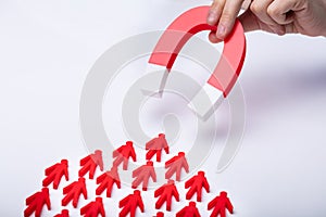 Businessman Attracting Red Team With Horseshoe Magnet photo