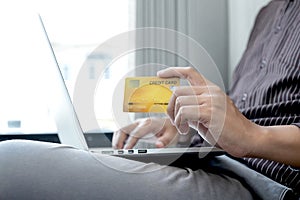 The businessman`s hand is holding a credit card and using a laptop for online shopping and internet payment in the office