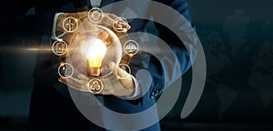 Businessman holding glowing light bulb with energy sources icon photo