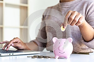The businessman`s hand holds the money in the piggy bank for saving money for future use