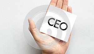Businessman`s hand in a pink shirt sleeve holding paper business card with text CEO sharp , closeup isolated over white backgroun